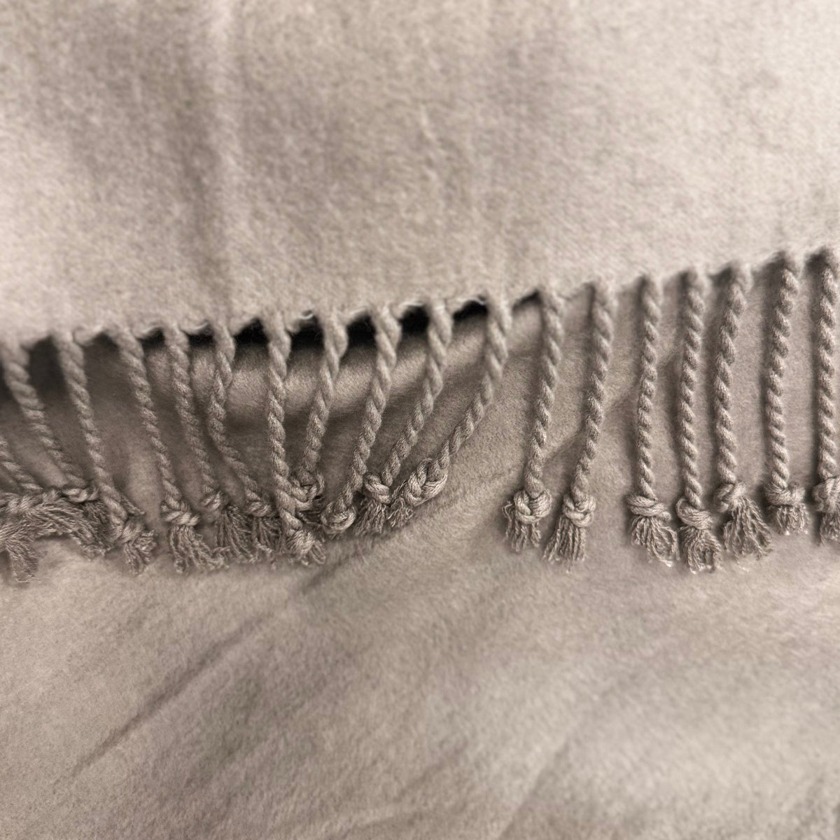 Close-up of a textured fabric with braided trim on a neutral background