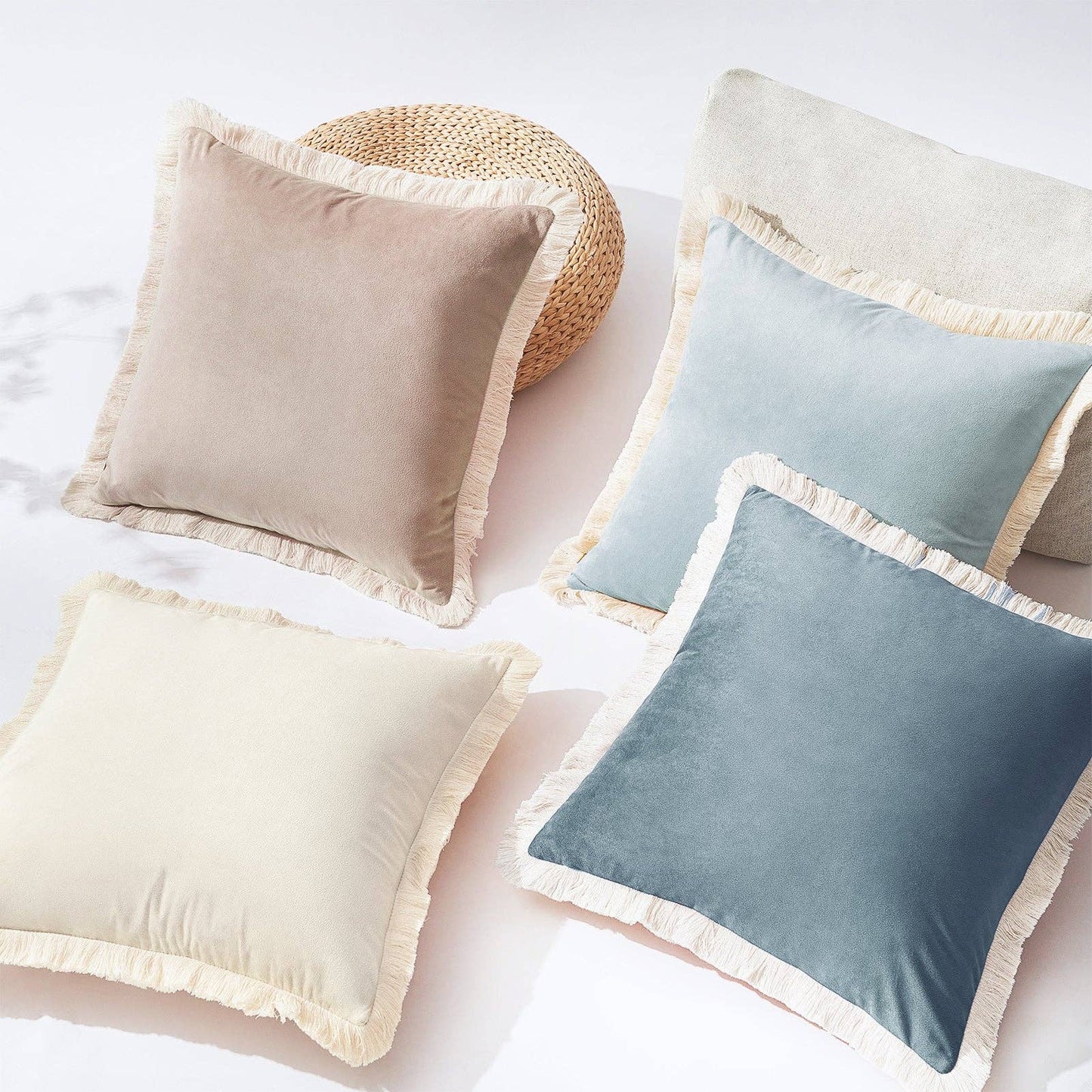 Four cushions with ruffled edges in beige, brown, and blue on a white surface.