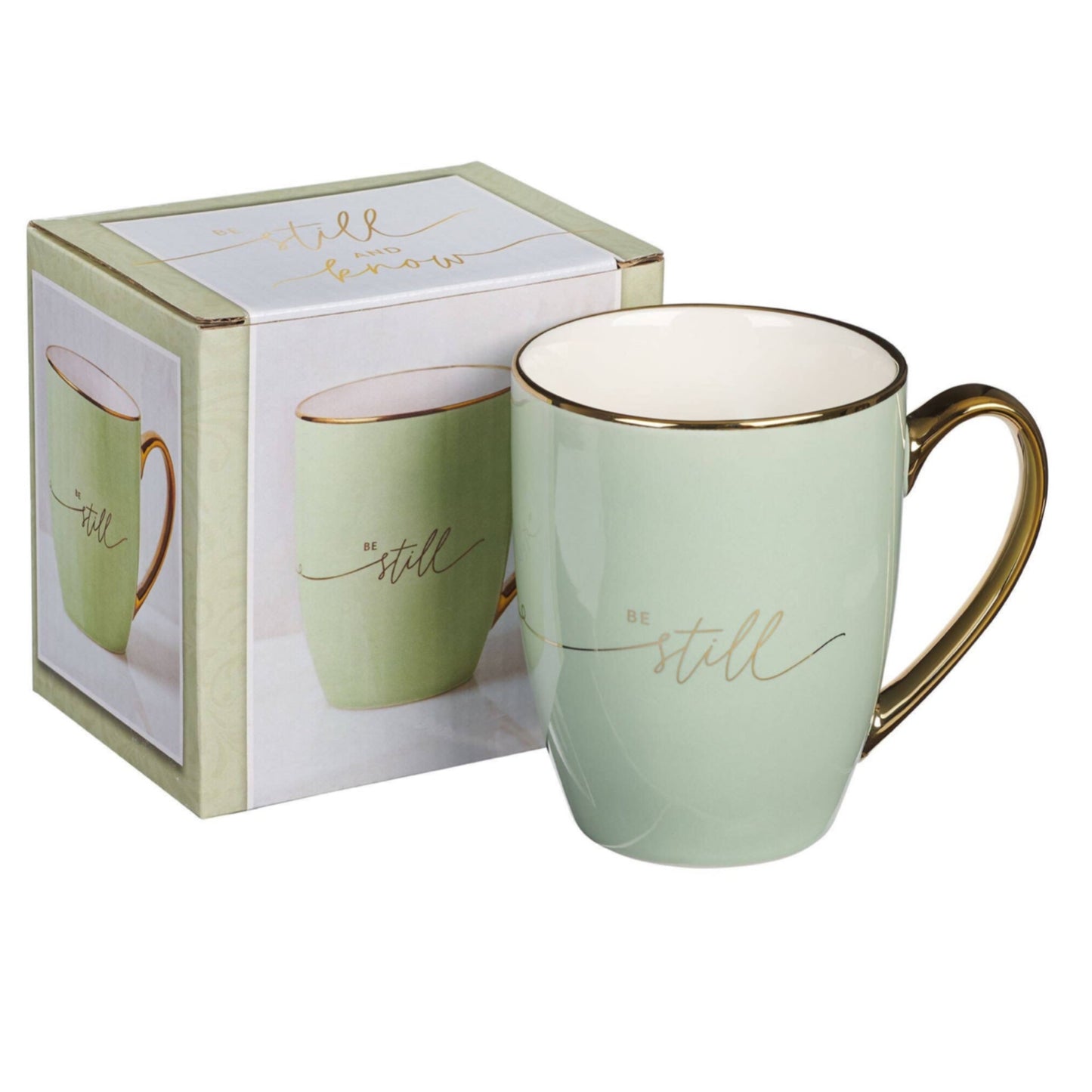 Green mug with gold handle and 'be still' text, displayed with packaging on a white background