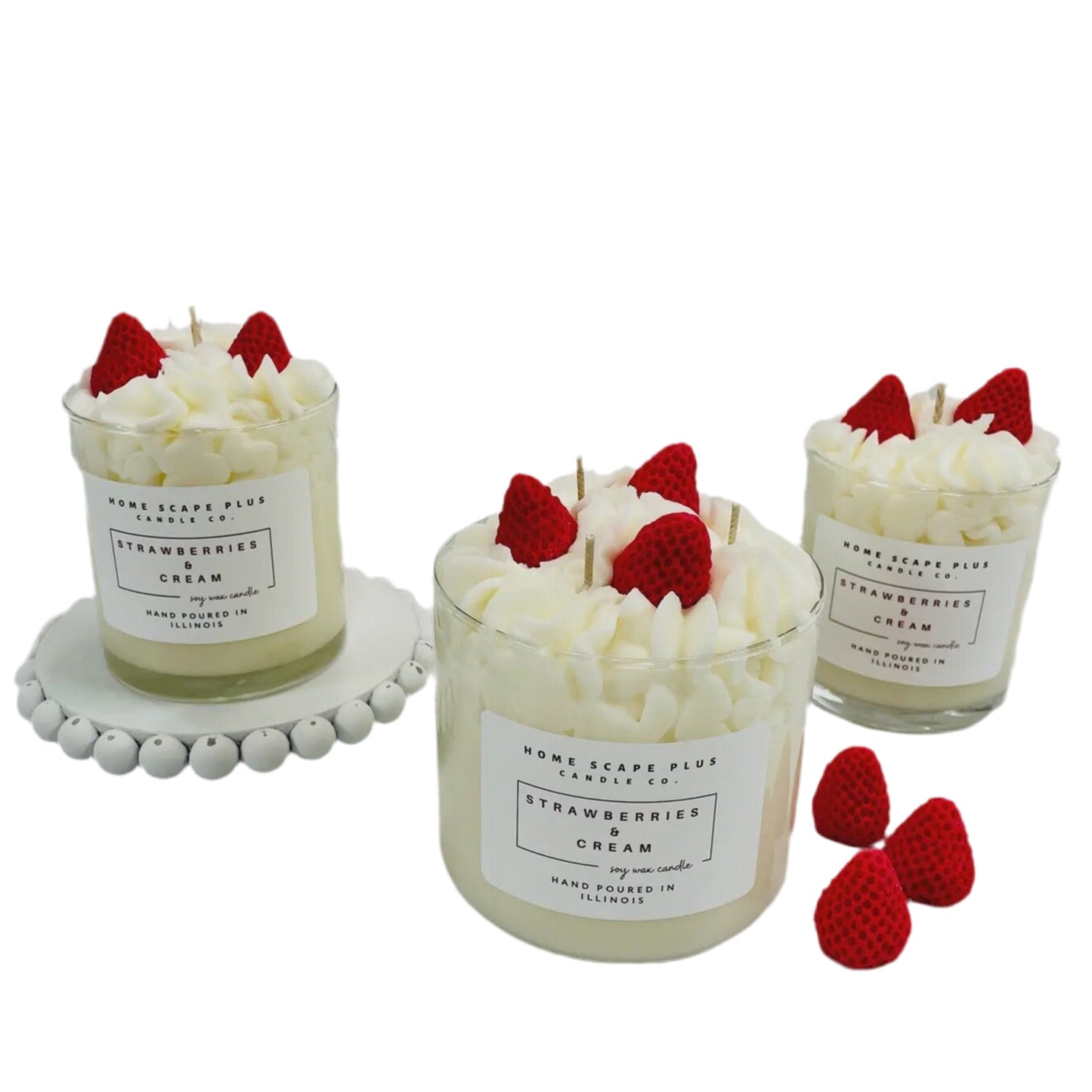 Three strawberry cream candles with red strawberries on top on a white background