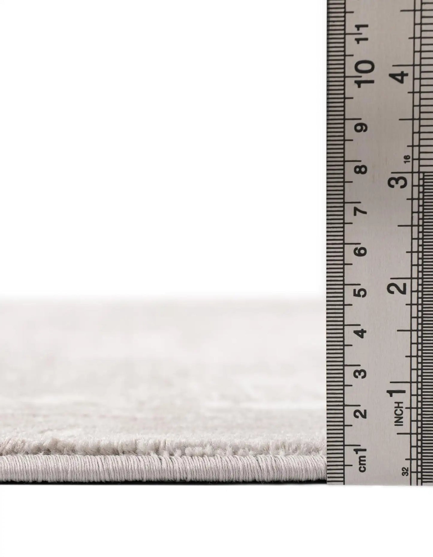 Close-up of a white rug with a ruler for scale on a white background