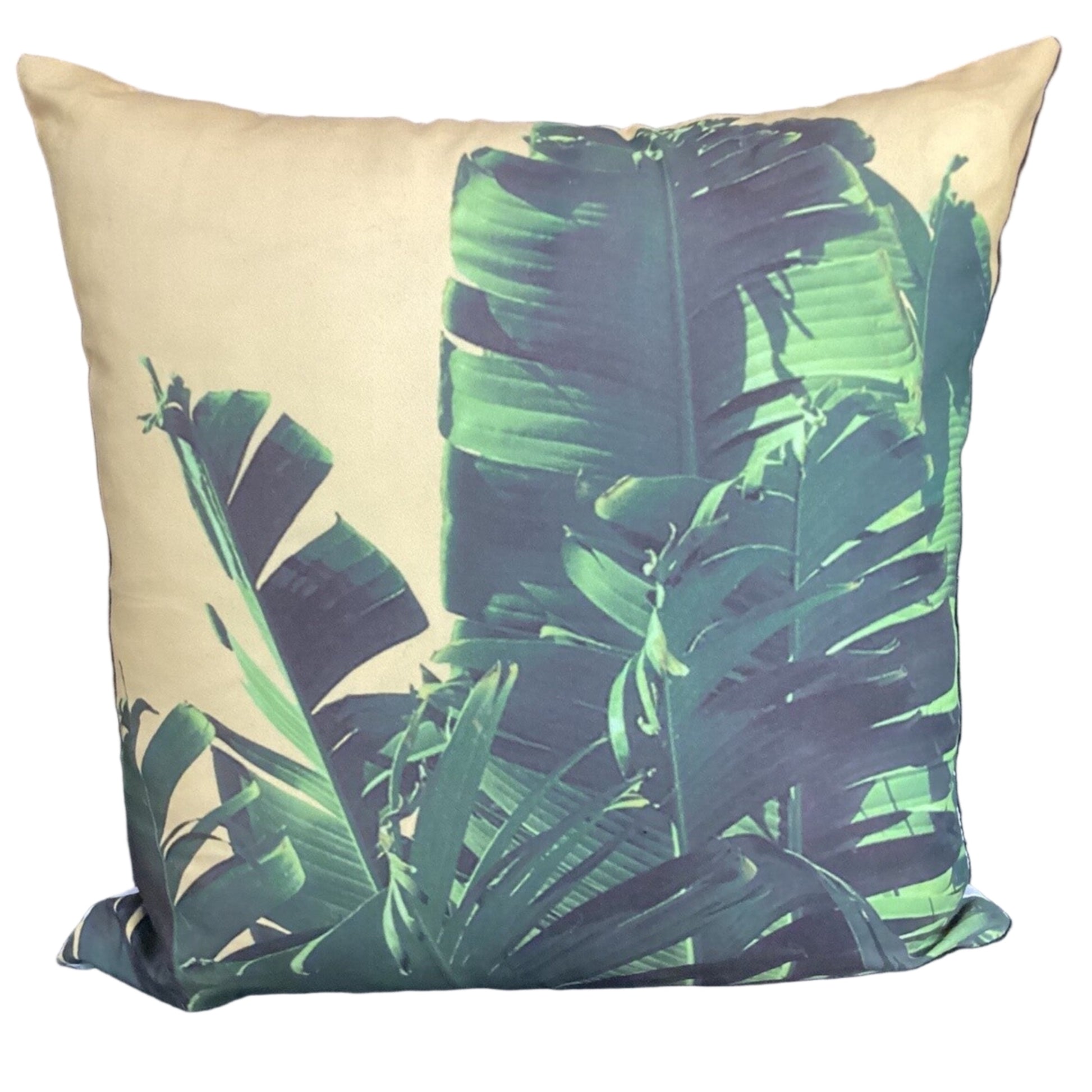 A square throw pillow featuring a tropical banana leaf pattern in shades of green and teal over a warm beige background, shown against a plain white studio backdrop.