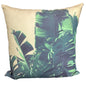 A square throw pillow featuring a tropical banana leaf pattern in shades of green and teal over a warm beige background, shown against a plain white studio backdrop.
