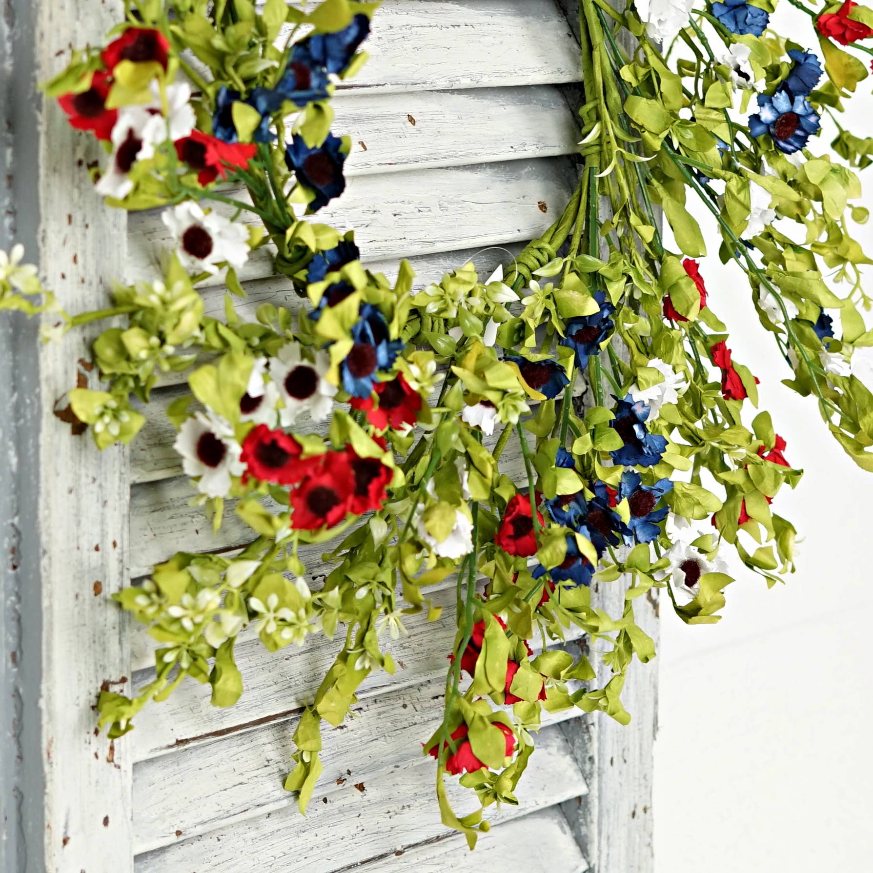 Decorative floral garland with red, blue, and white flowers on a wooden background