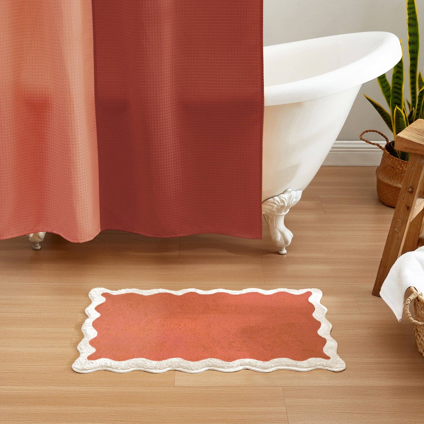 Bathroom with a red shower curtain and matching bath mat on wooden floor.