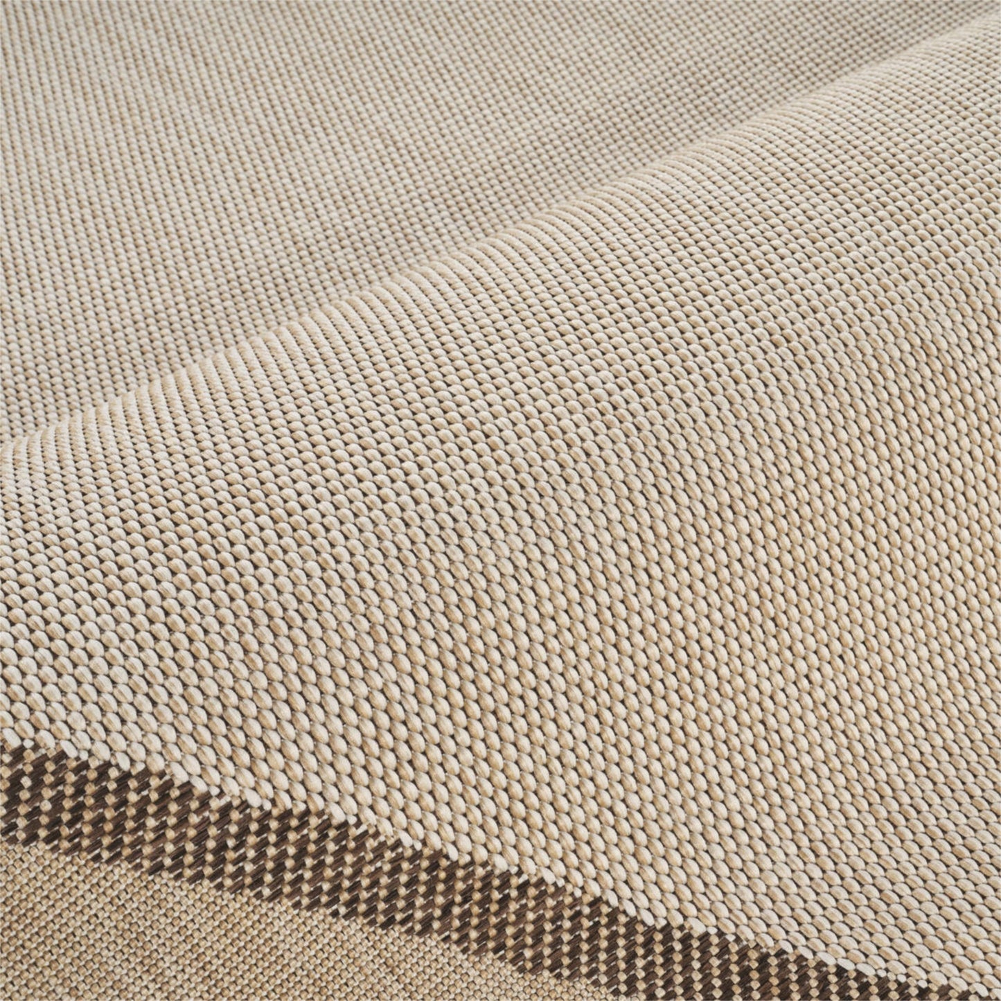 Close-up of a woven fabric texture in a light beige color, showing the detailed knit pattern and a folded edge.