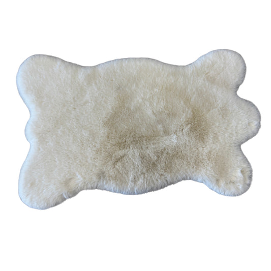 Beige faux fur rug shaped like a bear paw on a white background