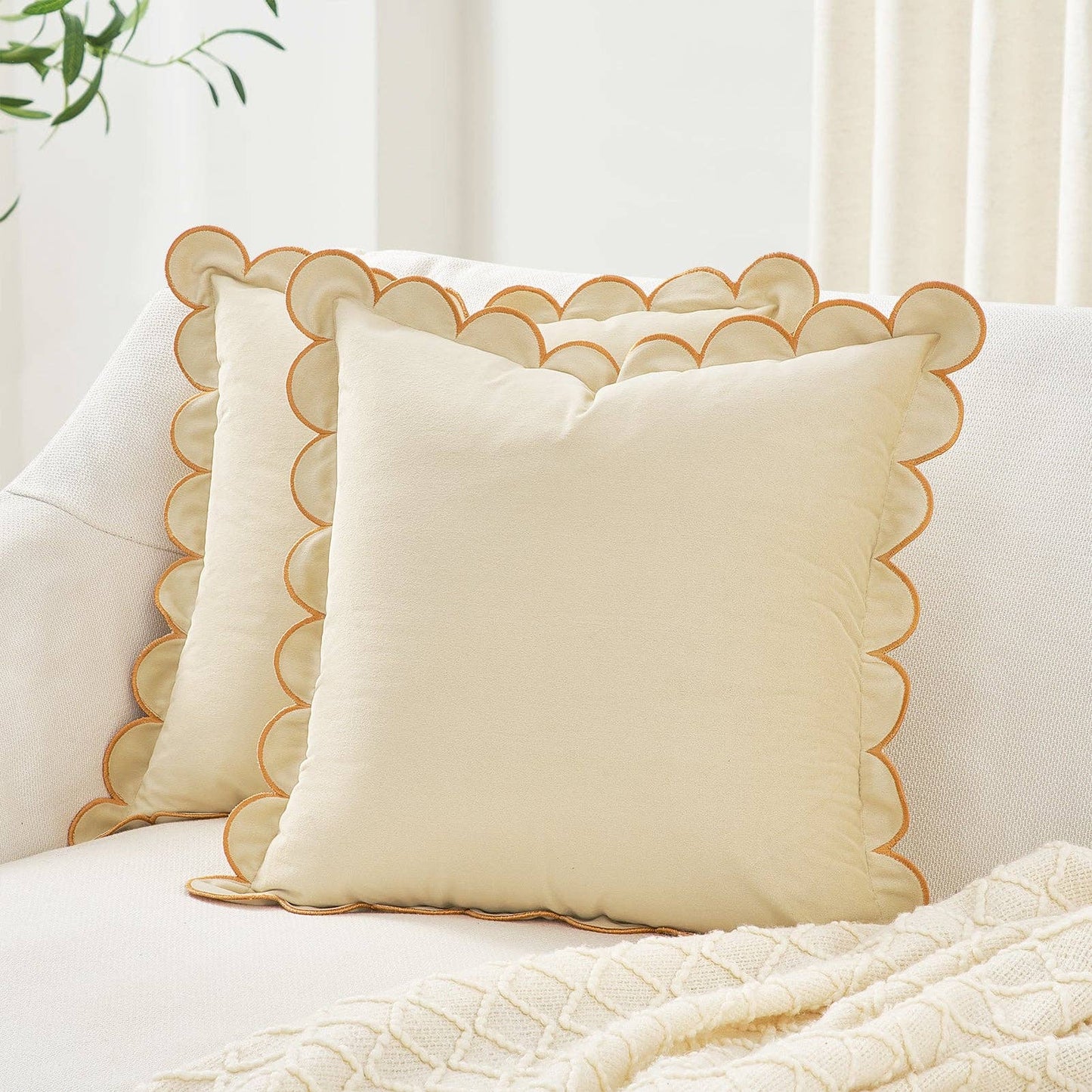 Beige pillow with scalloped edge on a white sofa