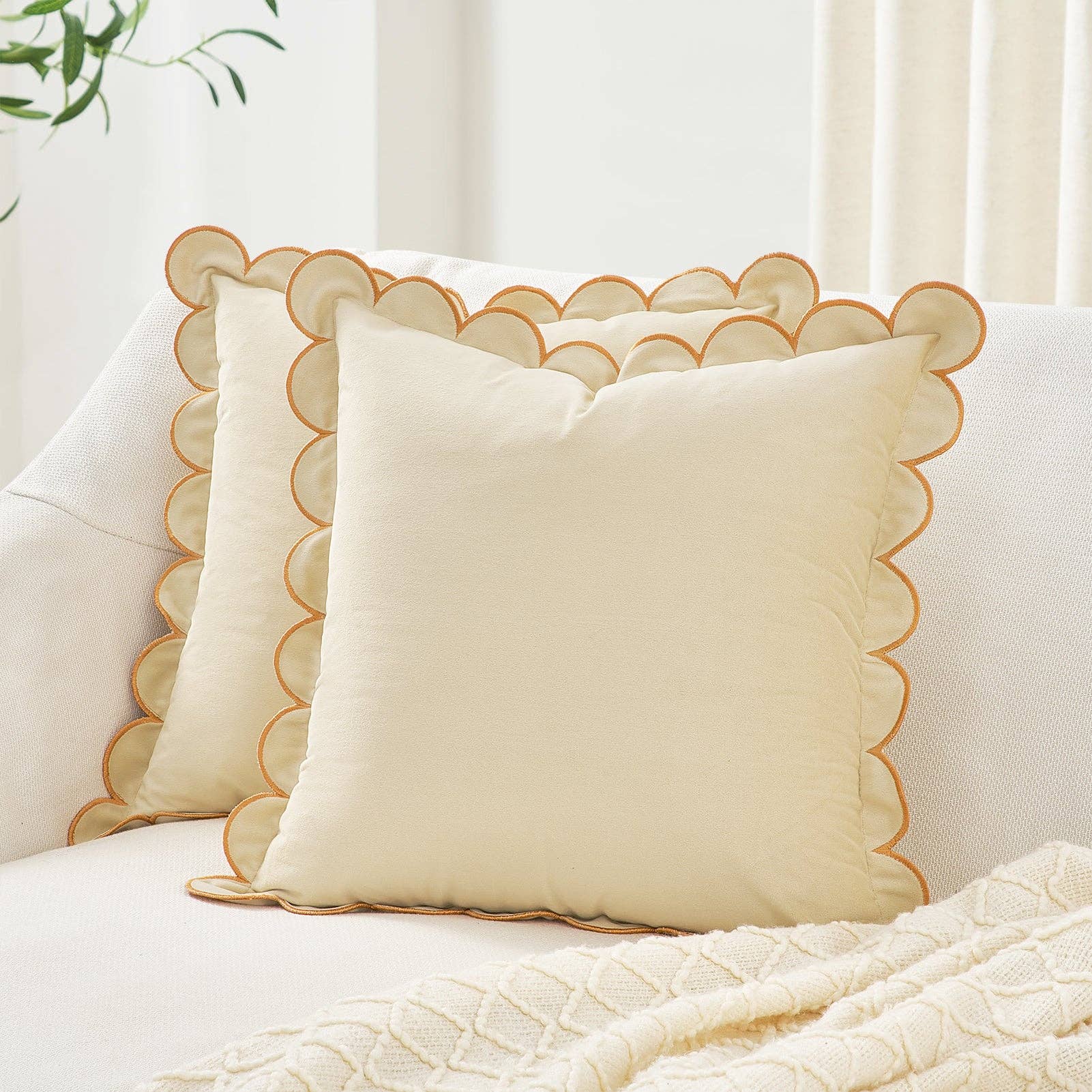 Beige pillow with scalloped edge on a white sofa