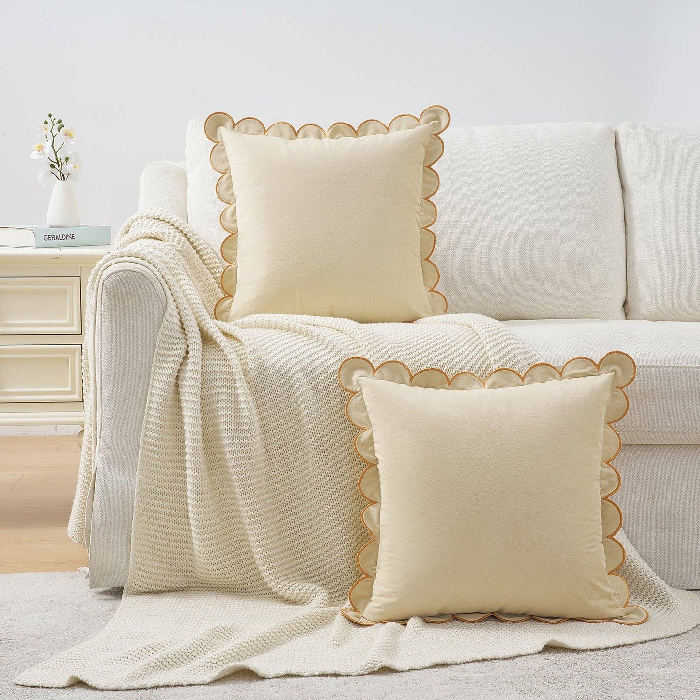 White sofa with decorative pillows and a blanket in a cozy living room setting.