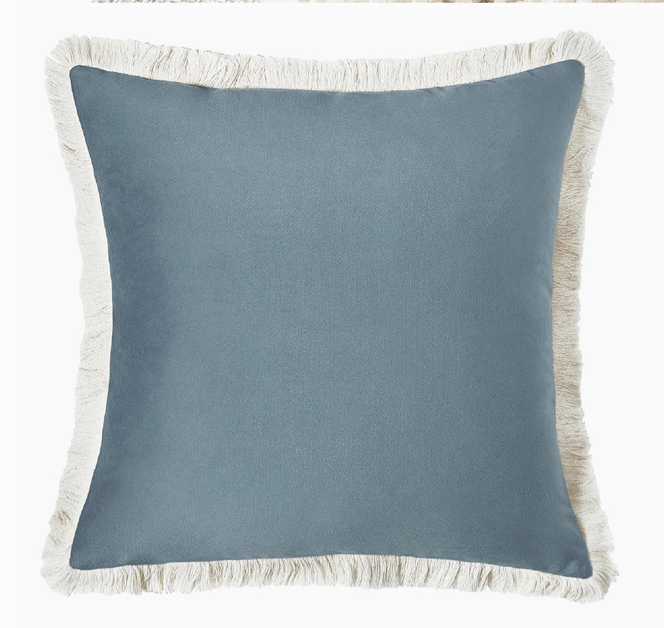 Blue pillow with white fringe on a white background