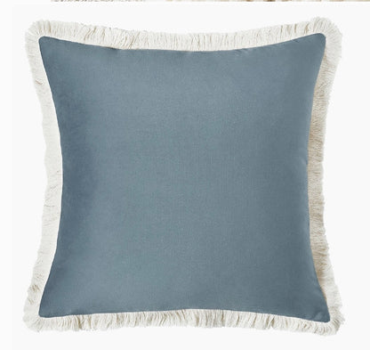 Blue pillow with white fringe on a white background