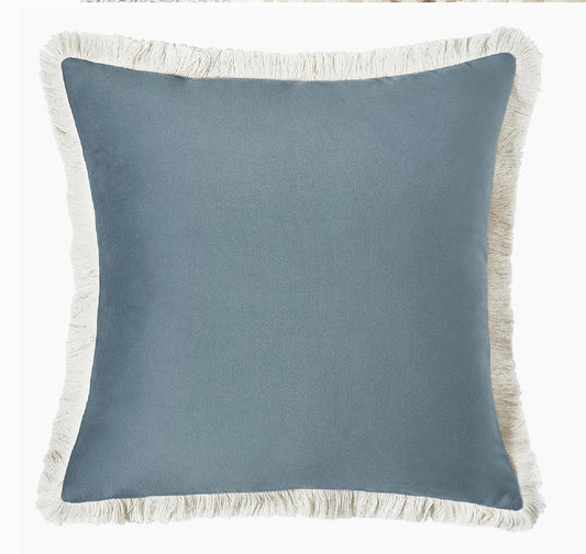 Blue pillow with white fringe on a white background