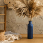 Blue vase with pampas grass against a textured wall
