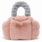 A plush, cloud-shaped Pur-Low in dusty pink faux fur with a matching gray ribbed handle and a small gold button closure on the front, set against a plain white background.