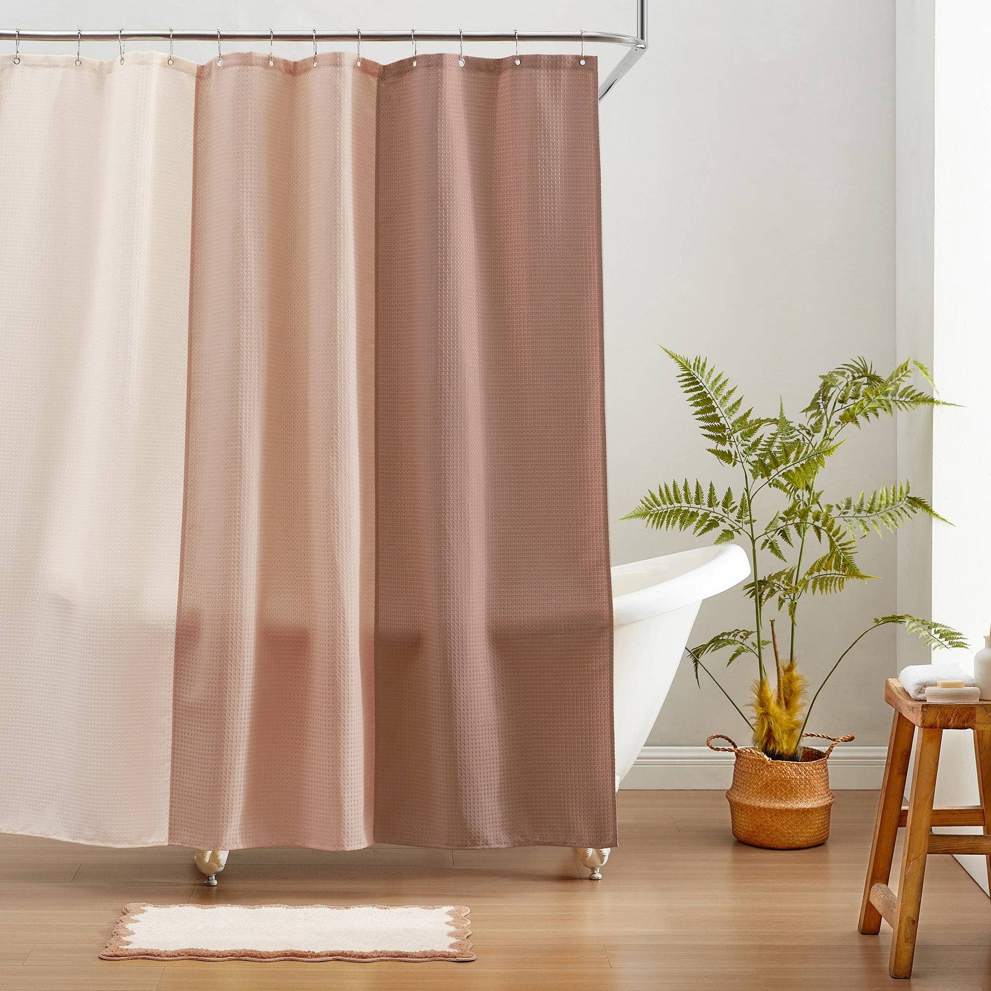 Brown shower curtain in a bathroom with a plant and stool.