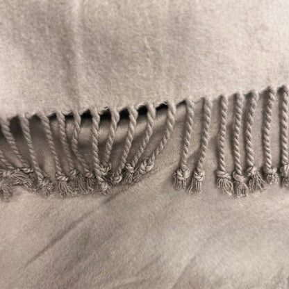 Close-up of a textured fabric with braided trim on a neutral background