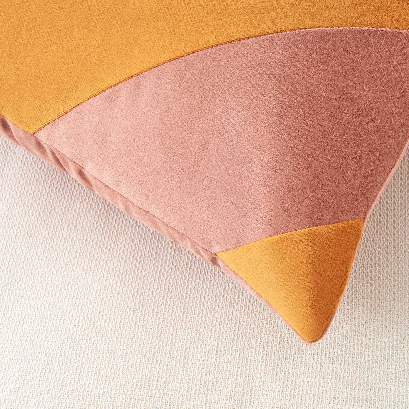 Color-blocked pillow with pink and mustard yellow sections on a white background