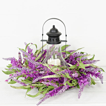 Decorative arrangement with purple flowers, green leaves, and a black lantern on a white background