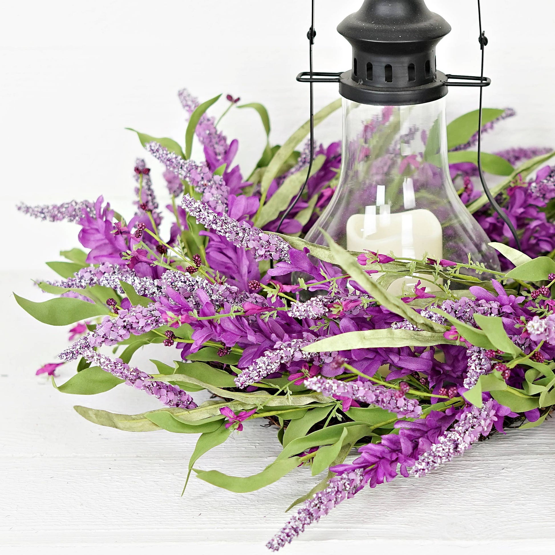 Decorative arrangement with purple flowers and a lantern on a white background