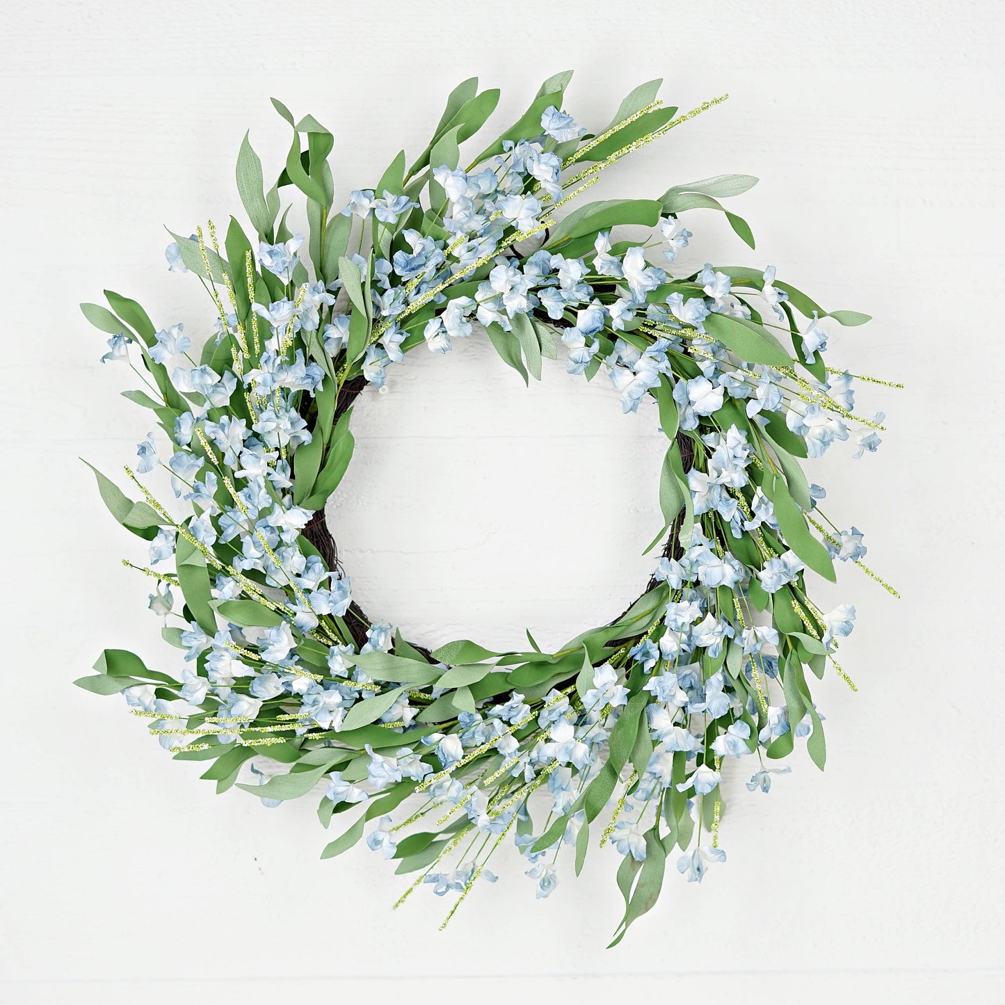 Decorative wreath with green leaves and small blue flowers on a white background