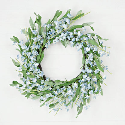 Decorative wreath with green leaves and small blue flowers on a white background