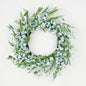 Decorative wreath with green leaves and small blue flowers on a white background