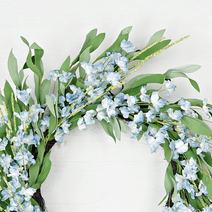 Decorative wreath with green leaves and small blue flowers on a white background