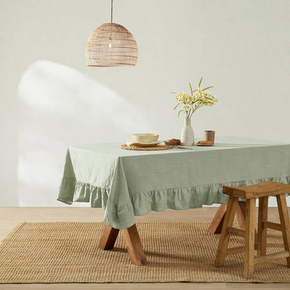 Dining room with a green tablecloth on a table, wooden stool, and decorative elements.