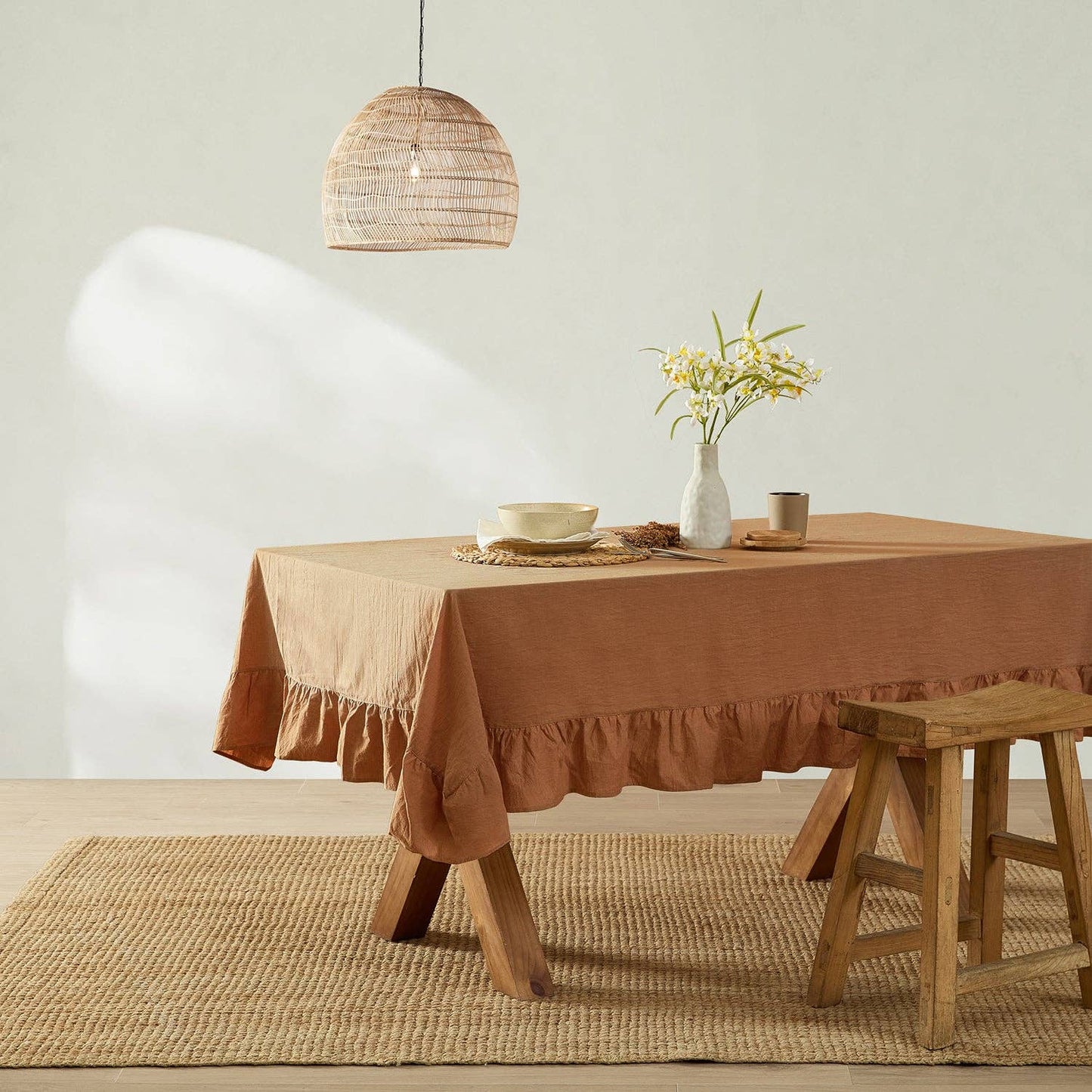 Dining room with a table covered by a brown tablecloth, wooden stool, and decorative elements.