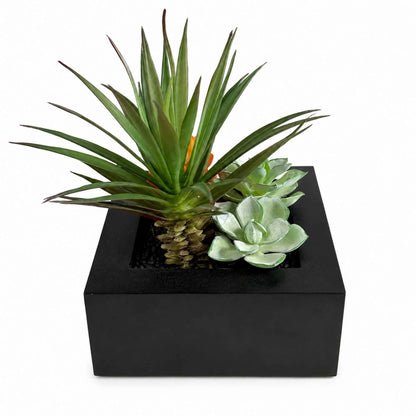 Faux plant arrangement with air plant and succulent in a black square planter box