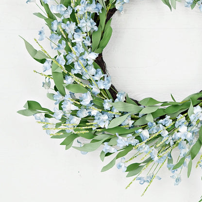 Floral wreath with blue flowers and green leaves on a white background