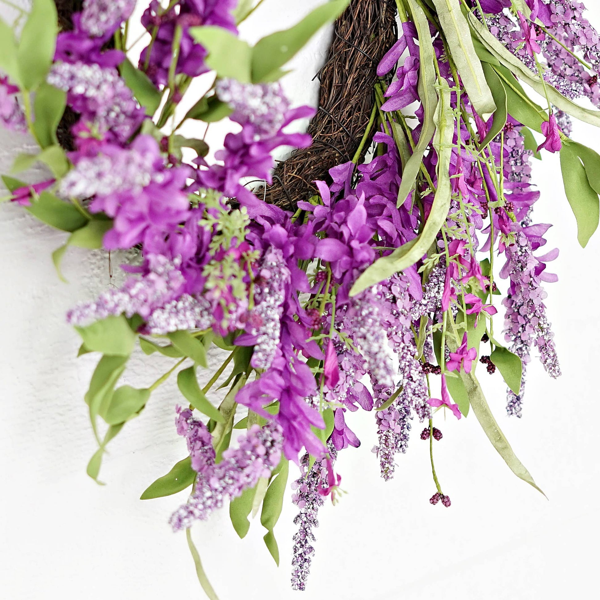 Floral wreath with purple flowers and green leaves on a white background