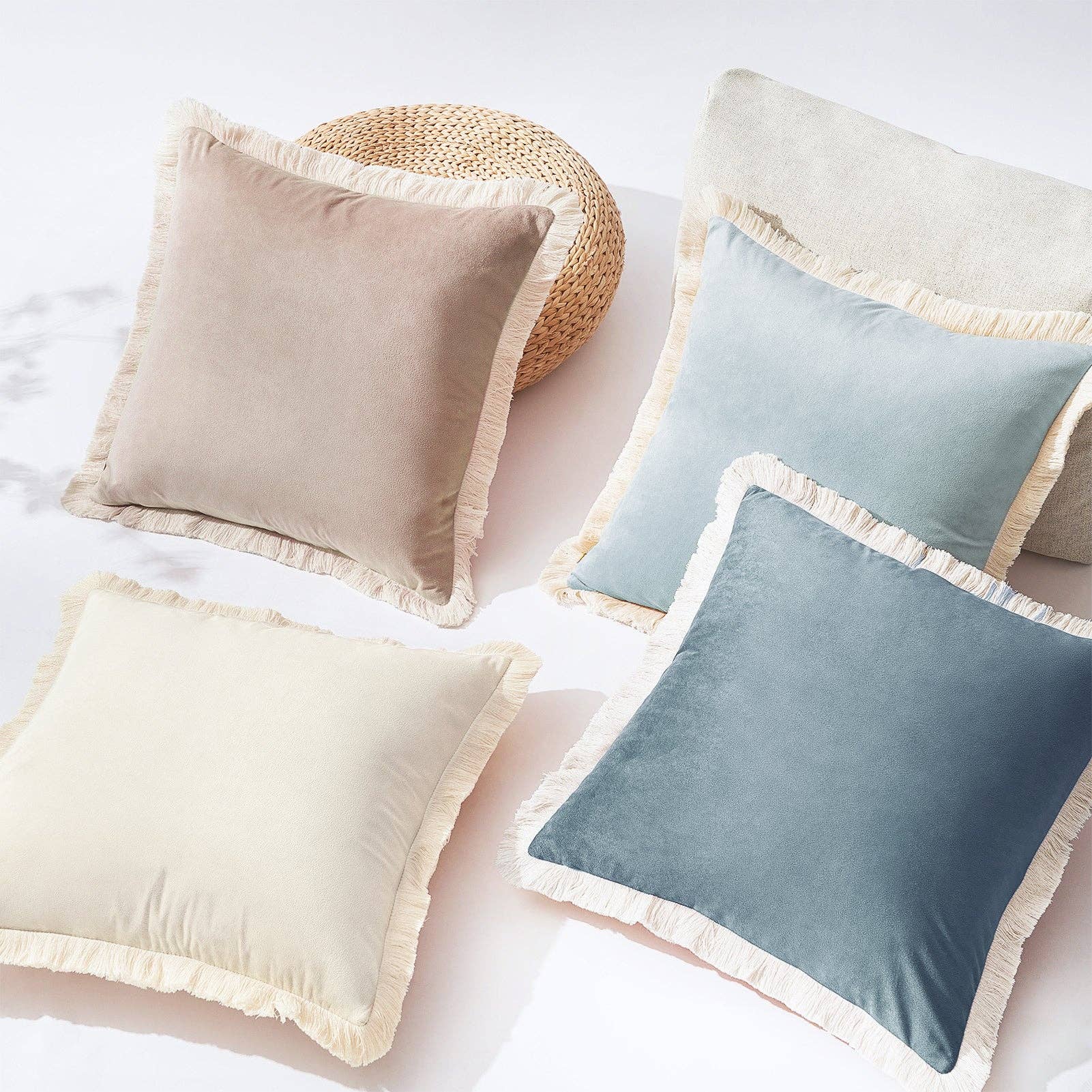 Four cushions with ruffled edges in beige, brown, and blue on a white surface.