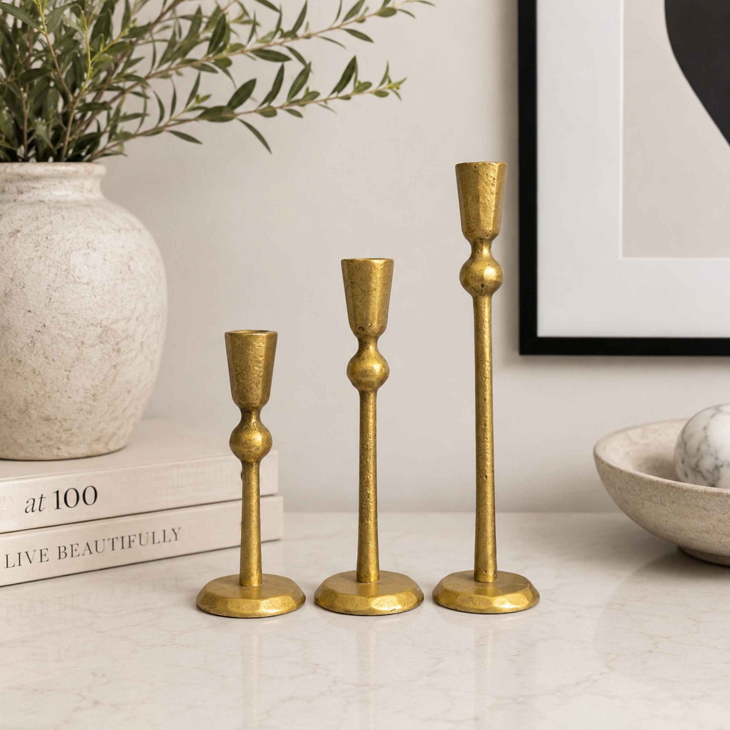 Three gold candle holders on a table.