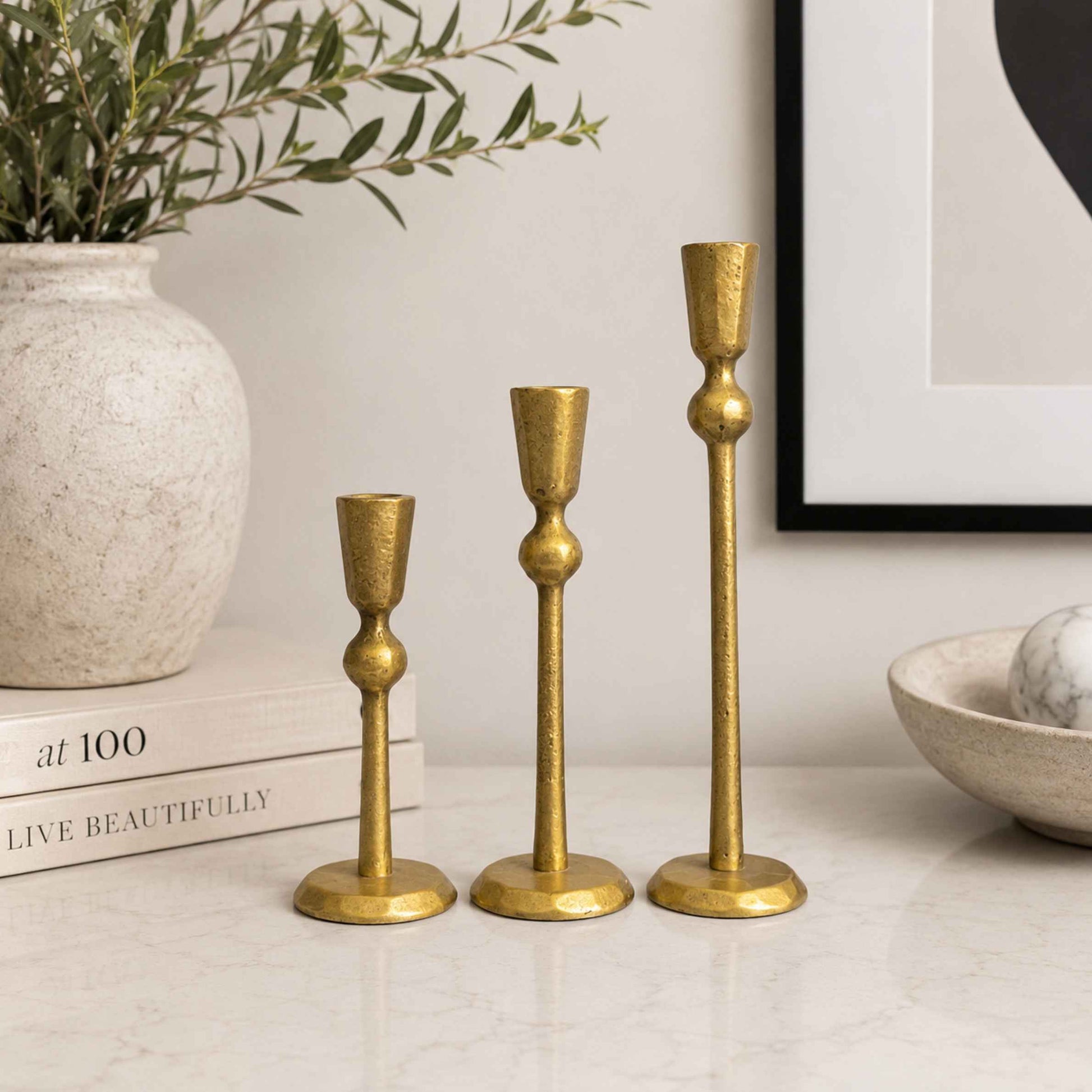 Three gold candle holders on a table.