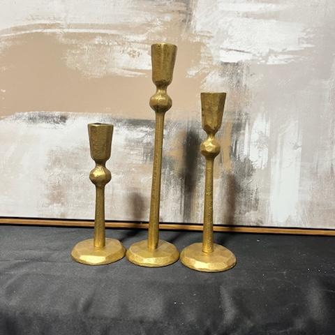 Three gold candle holders on a table.