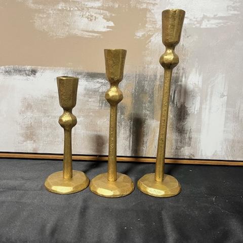 Three gold candle holders on a table.