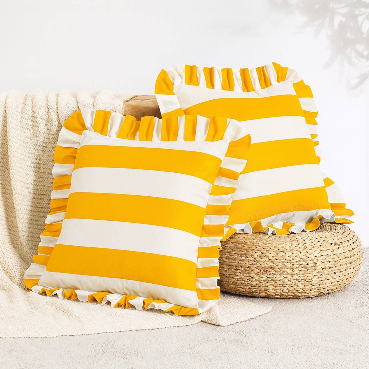 Yellow and white striped pillows with ruffles on a neutral background