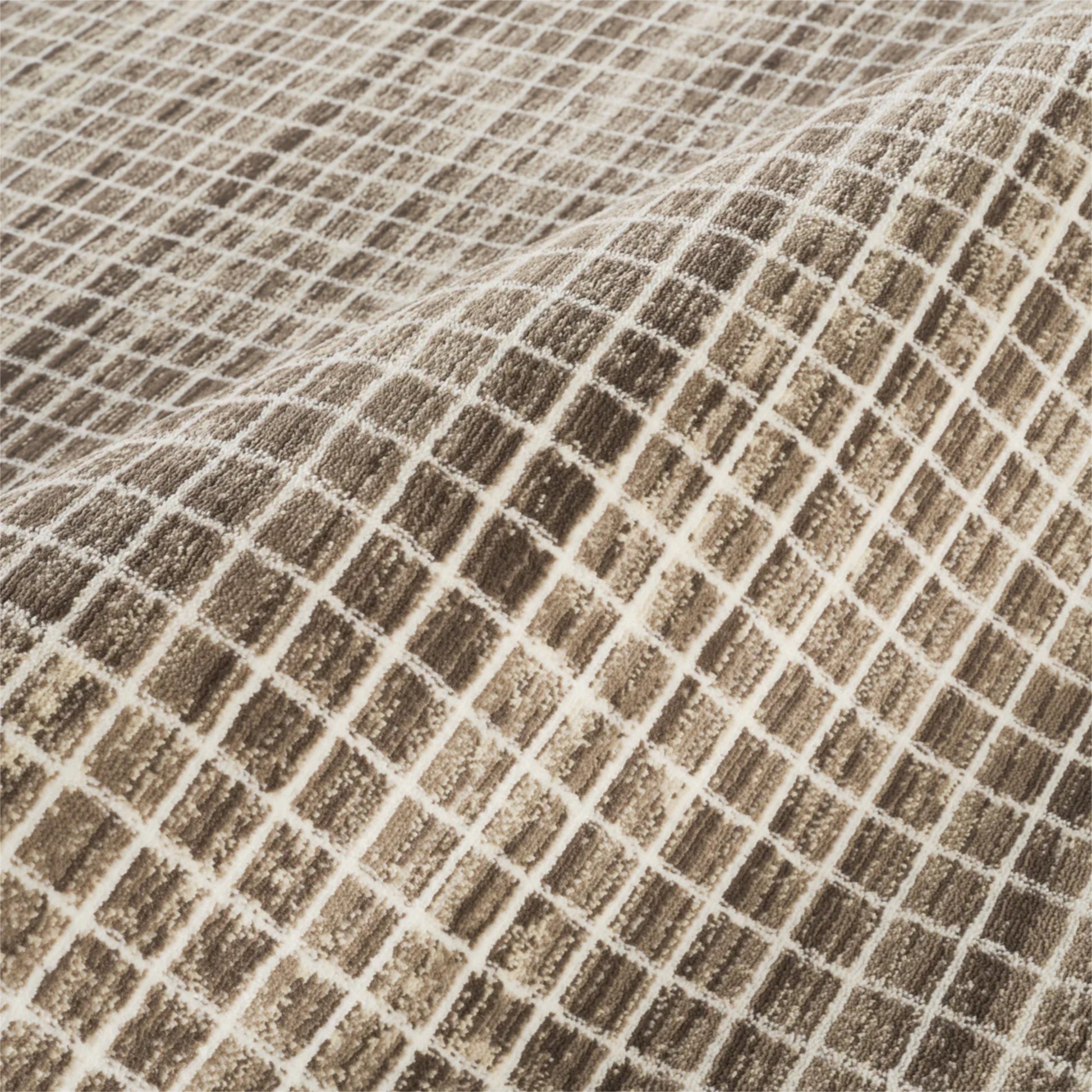 A close-up of a woven fabric with a textured grid pattern in brown and beige.