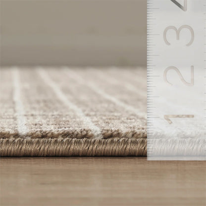 Close-up of a beige textured rug, shown on a wooden floor next to a white ruler for scale.