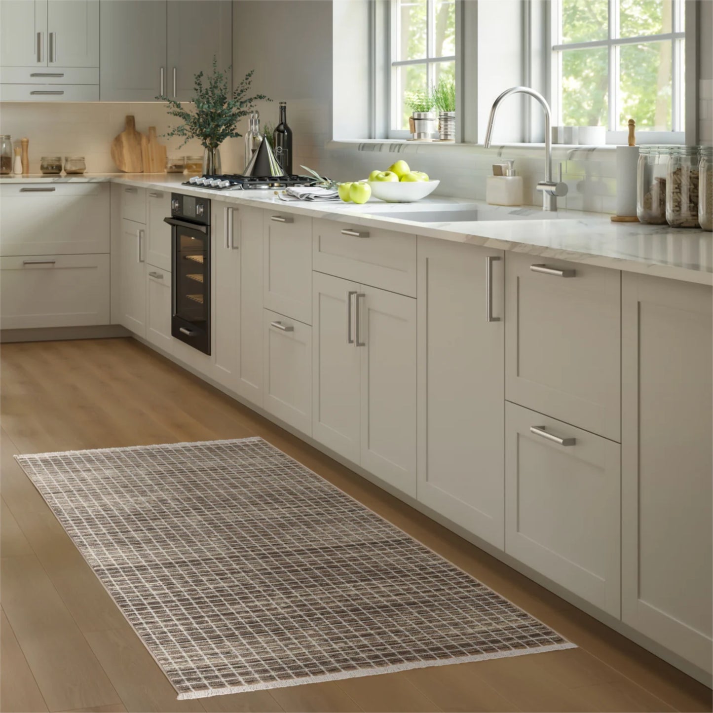 A rectangular area rug with a gray and white grid pattern is shown on a light wood floor in a modern kitchen setting.