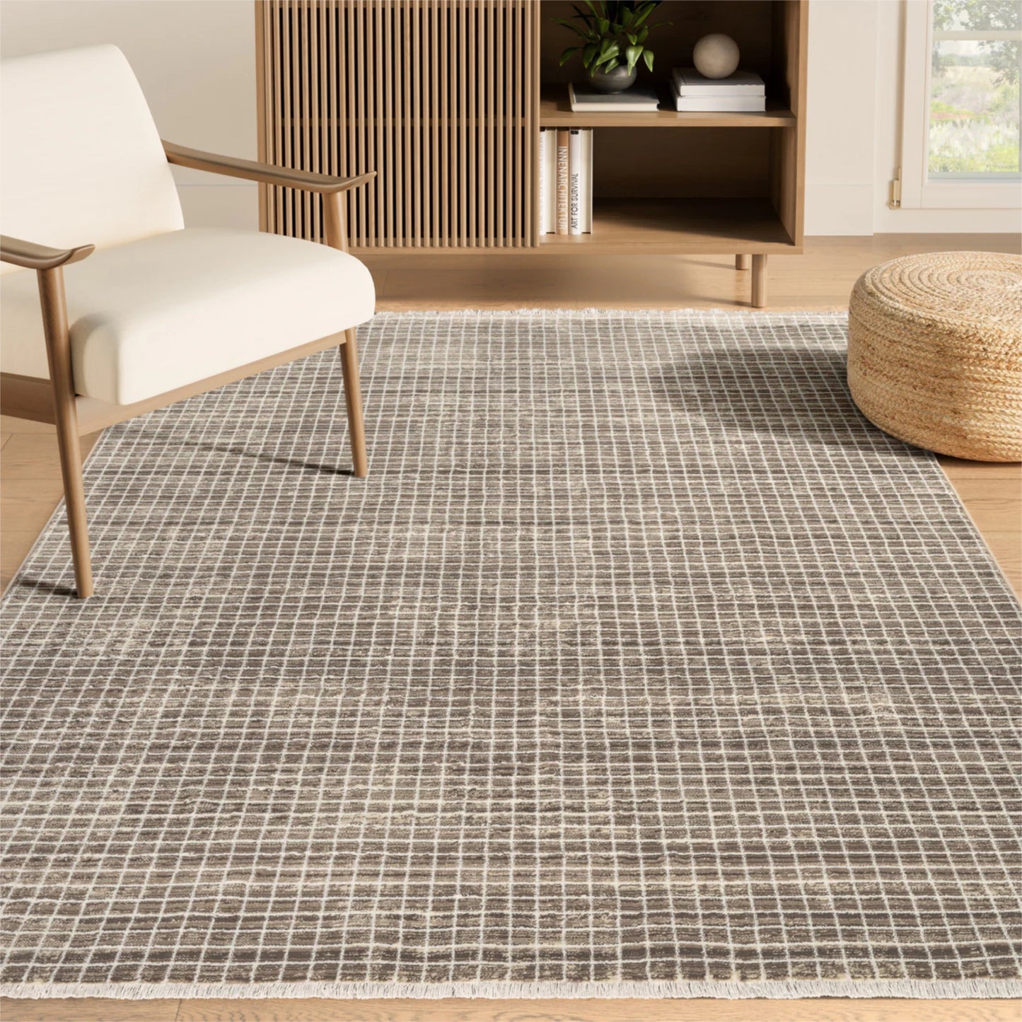 Living room with a grid-patterned rug, white chair, and wooden ottoman.