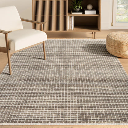 Living room with a grid-patterned rug, white chair, and wooden ottoman.
