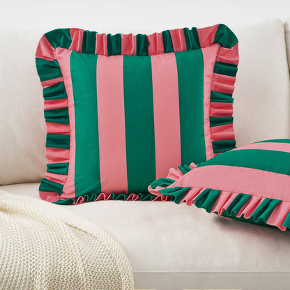 Striped pink and green pillow with ruffled edges on a beige sofa.