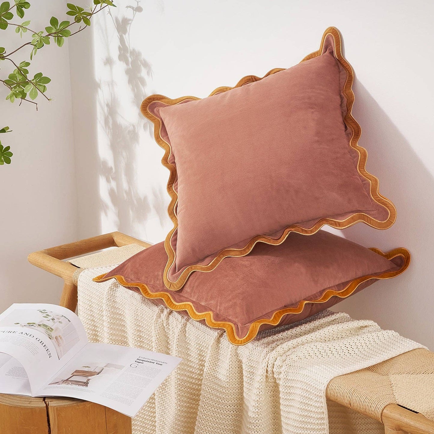 Pink cushions with scalloped edges on a wooden chair with a white wall background