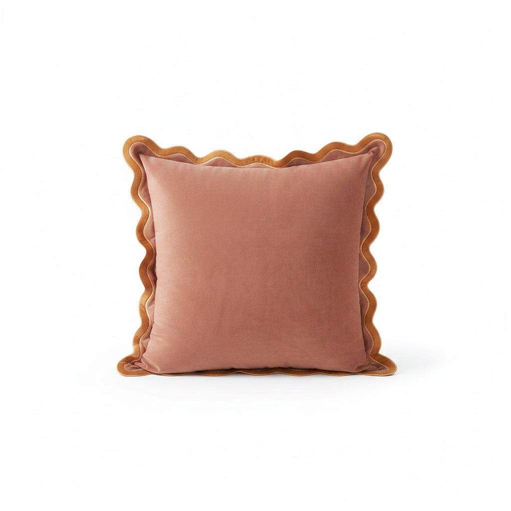 Pink pillows with scalloped edges on a white sofa in a living room setting.