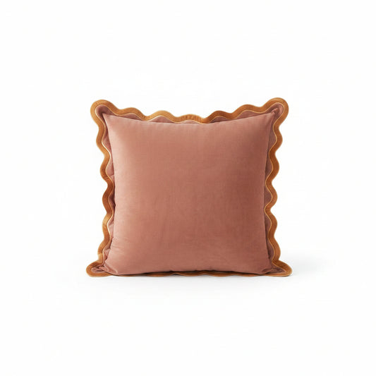 Pink pillows with scalloped edges on a white sofa in a living room setting.