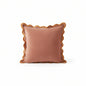 Pink pillows with scalloped edges on a white sofa in a living room setting.