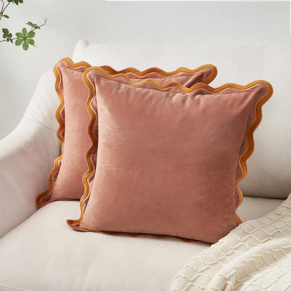 Pink velvet pillows with scalloped edges on a light-colored sofa.